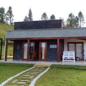 Casa prefabricada con fachada oscura y camiino de piedra