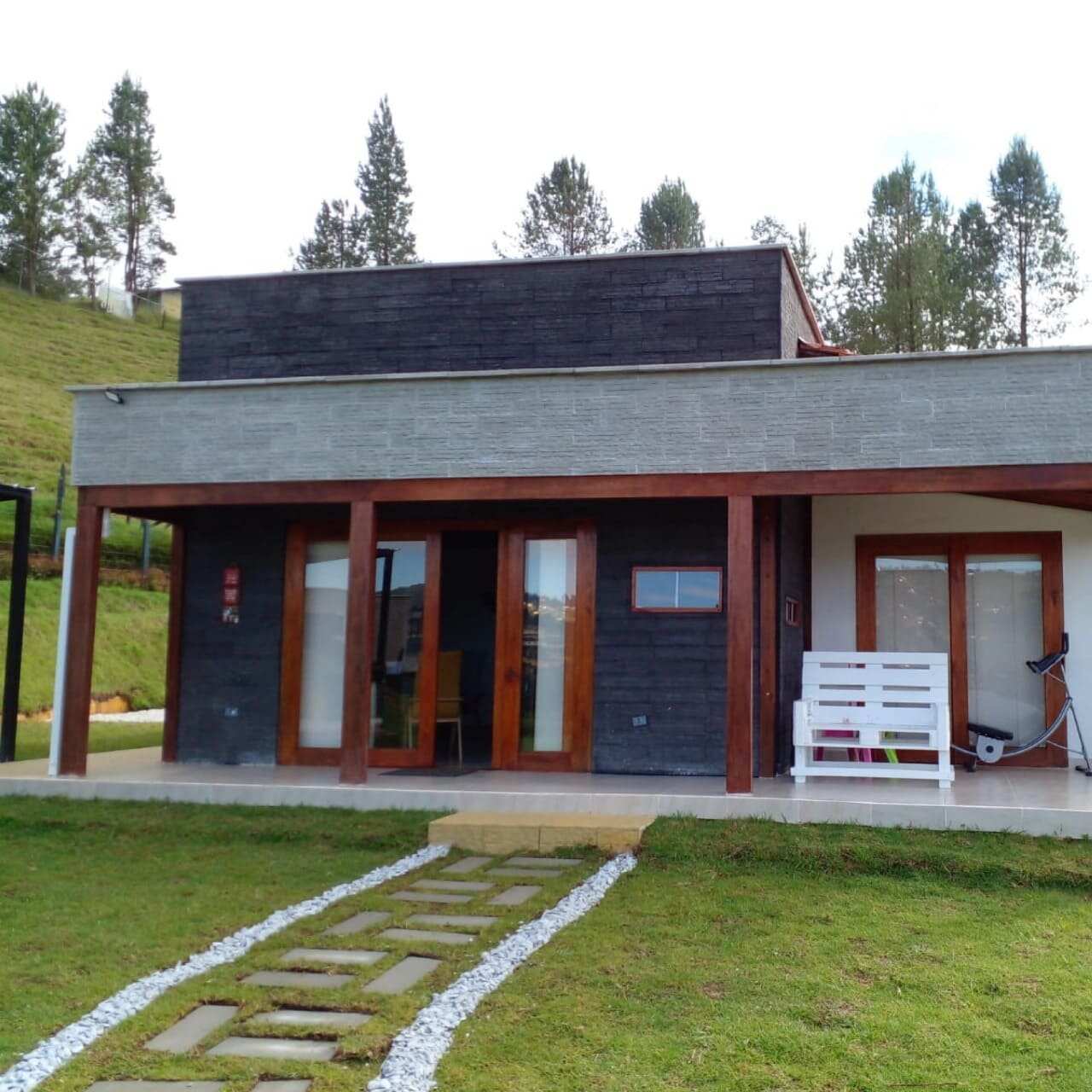Casa prefabricada con fachada oscura y camiino de piedra